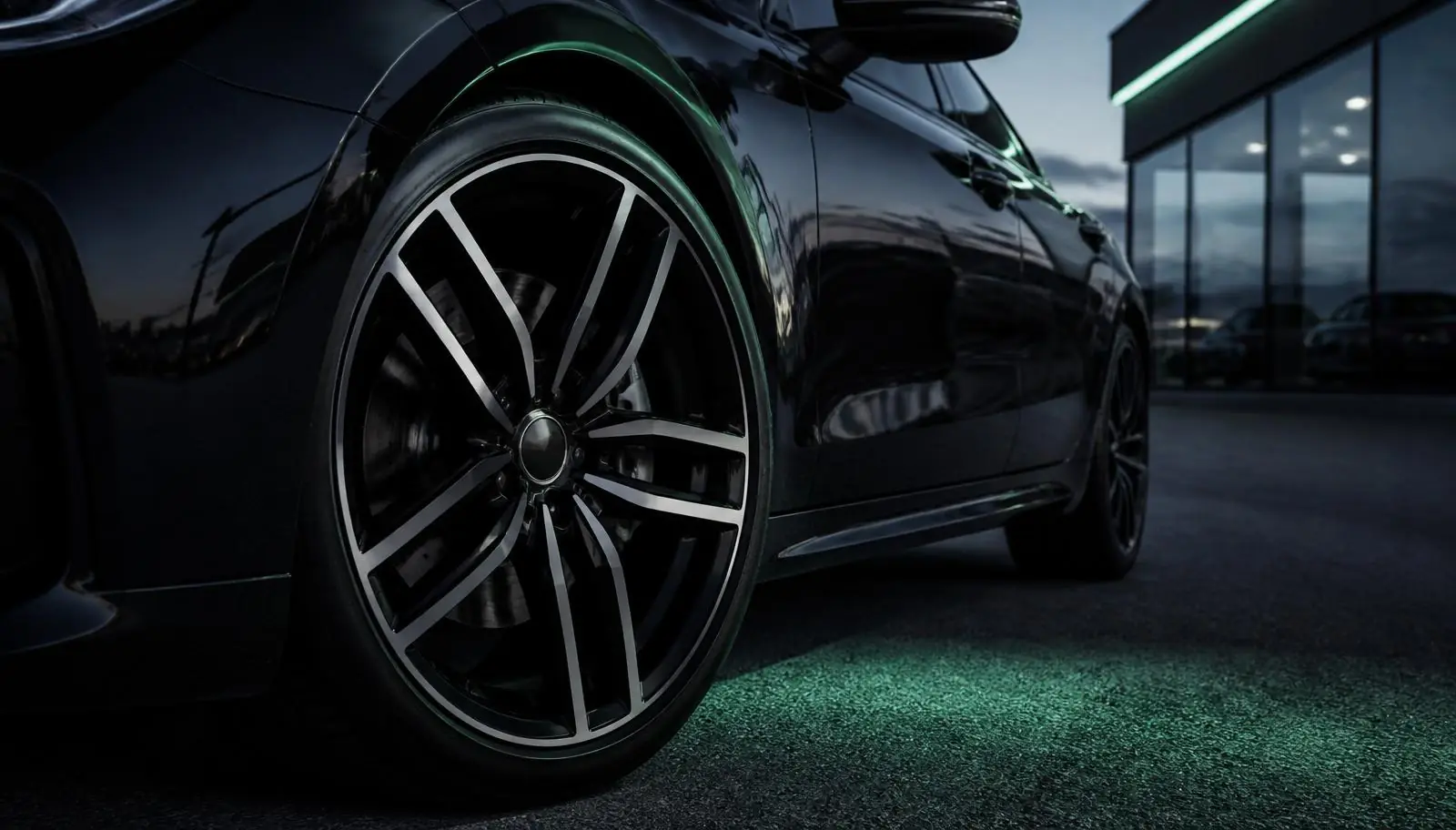 Freshly refurbished diamond-cut alloy wheel on a dark premium car at a West Midlands dealership forecourt at dusk